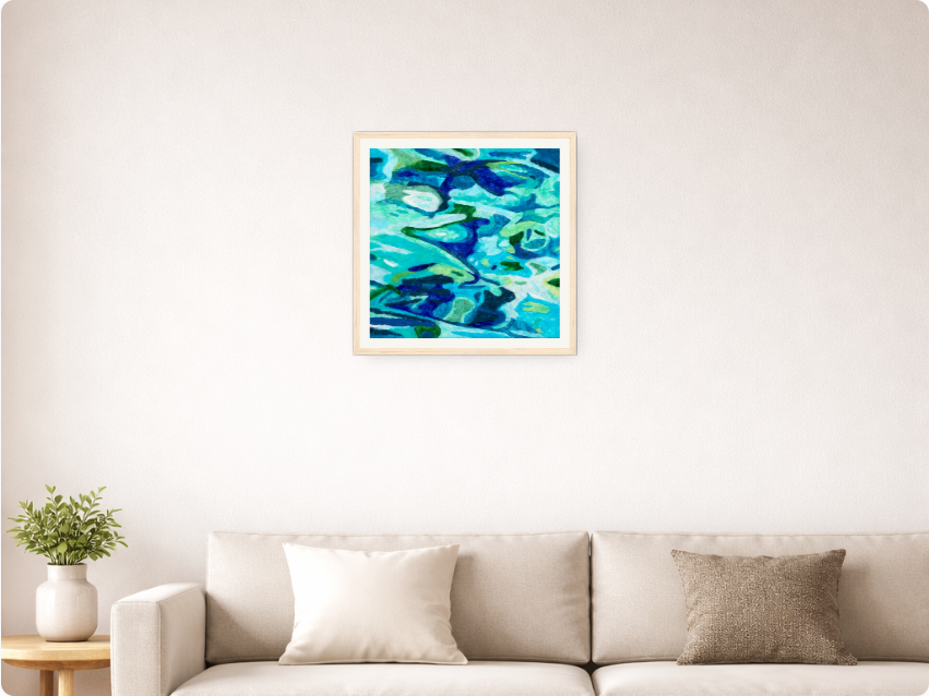 The artwork Aegean Waters in a natural wood frame with an off-white mat, previewed on a living room wall.